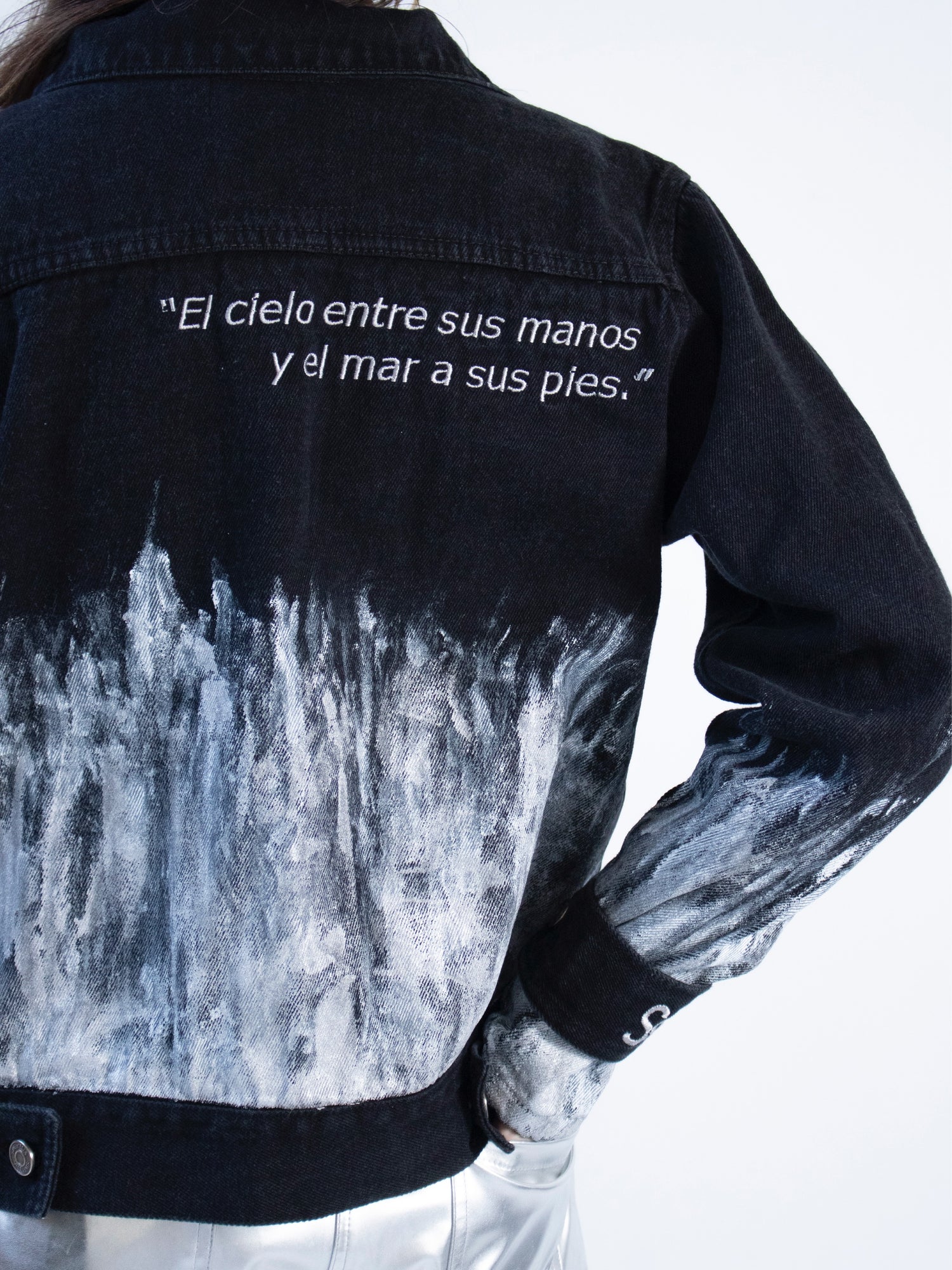 Chaqueta en denim negro con pintura plateada y bordados en espalda y puños.